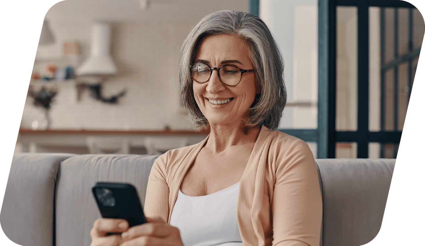 A woman browsing her phone with her laptop on her lap