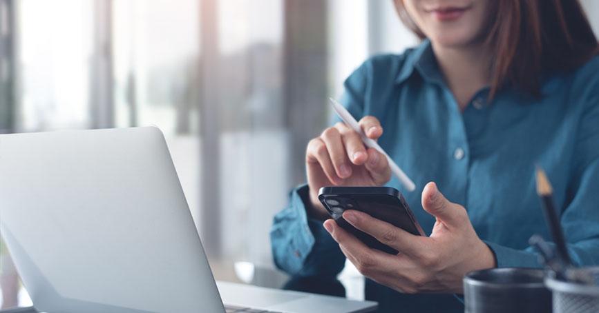 A woman using a phone and laptop